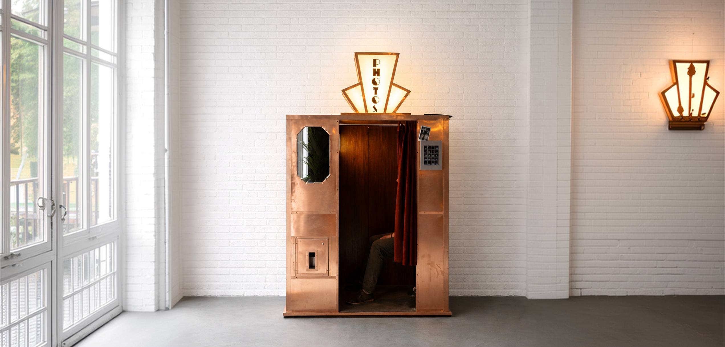 The Brasso booth — copper-clad photo booth with art deco PHOTOS sign